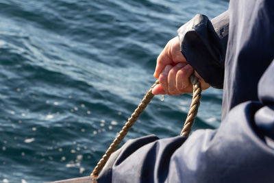 Midsection of man holding rope in sea