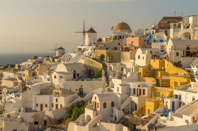 Scenic sunset at oia, santorini, with windmills, whitewashed houses, one yellow building and the sea