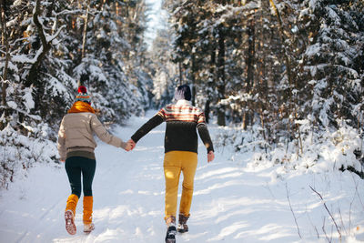 Rear view of women walking on snow covered mountain