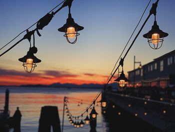 Illuminated street light against sky at sunset