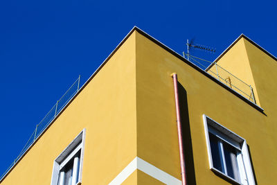 Urban construction in rome, residential building, painted yellow, blue sky.