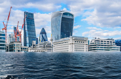 Modern buildings in city against cloudy sky