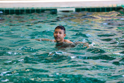 Portrait of shirtless boy swimming in pool