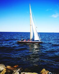 Sailboat sailing on sea against blue sky