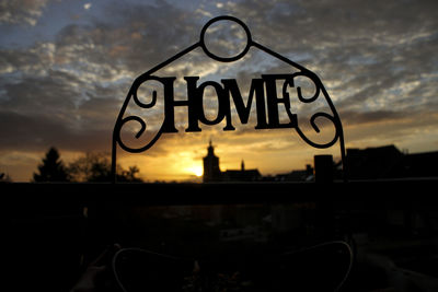 Close-up of sign against sky at sunset