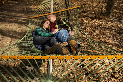 Couple embraces relaxing in hammock in fall leaves