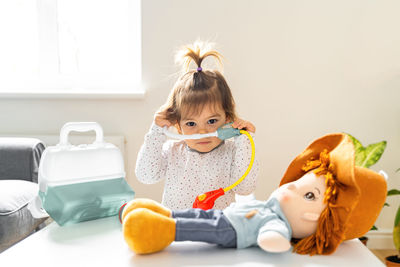 Close-up of cute girl sitting with toy at home