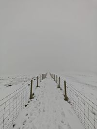 People skiing on snow covered field against clear sky