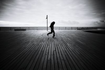 Rear view of girl walking on wooden flooring