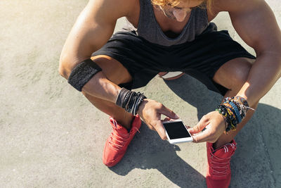 High angle view of athlete using mobile phone while sitting on road