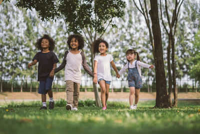 Smiling friends looking away while walking at park