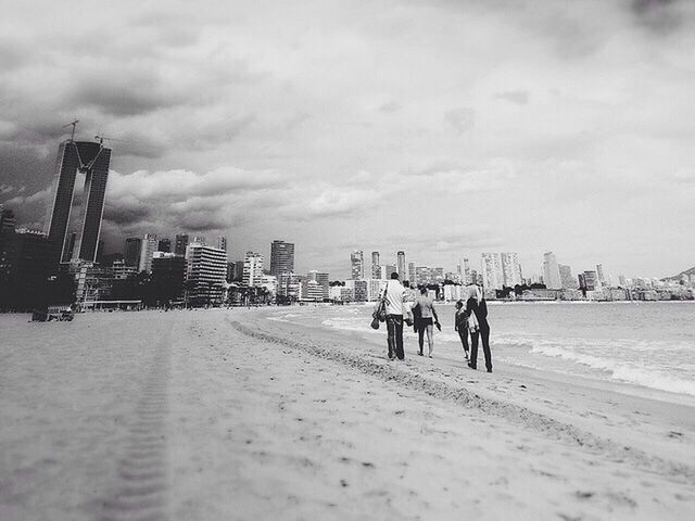 men, sky, building exterior, architecture, built structure, person, walking, lifestyles, city, leisure activity, cloud - sky, large group of people, rear view, full length, city life, beach, cloudy, cloud, day