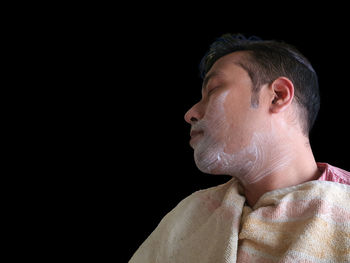 Close-up portrait of a man wearing hat against black background