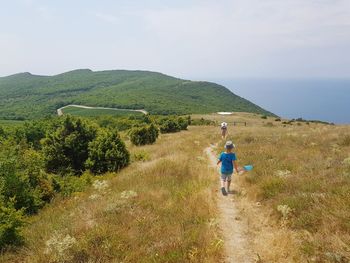 Rear view of man walking on trail against sky