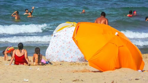 Rear view of people sitting on beach