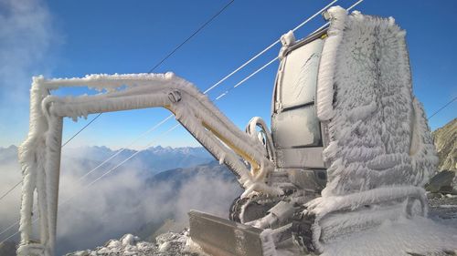 Frozen excavator at construction site against clear blue sky