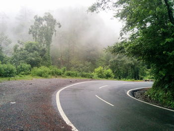 Empty road with trees in background