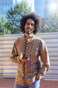 Young man using phone while standing in city