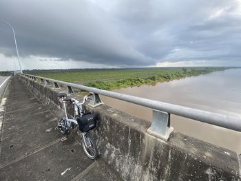 Bicycle on railing against sky during rainy season