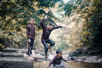 Multiple image of boy jumping into river in forest