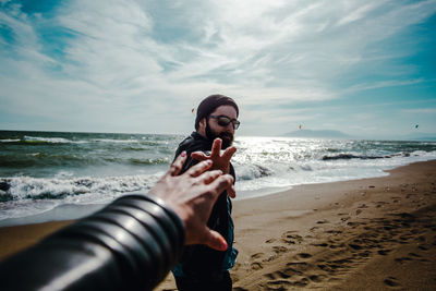 Man photographing at beach against sky