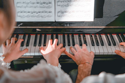 Cropped image of people playing piano at home