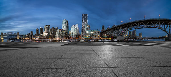 Illuminated bridge and buildings against sky in city