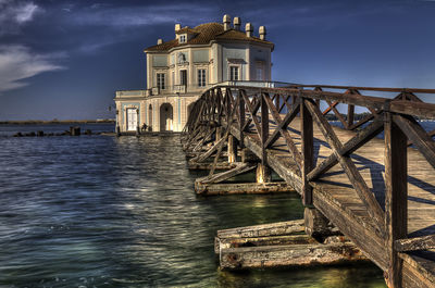 Bridge over river by building against sky