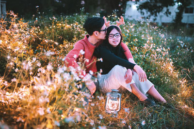 Man kissing on girlfriend head amidst flowering plants