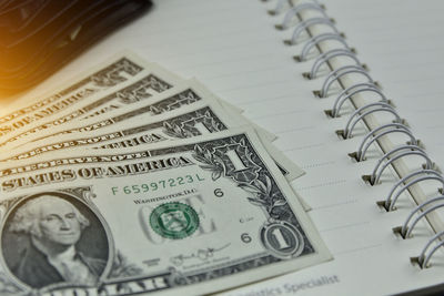 Close-up of paper currencies on spiral notebook