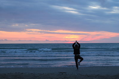 Man standing on beach against sky during sunset
