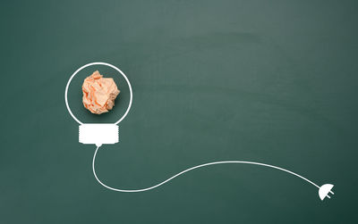 Crumpled sheet of paper on a green background, shape of a light bulb. energy saving concept, new 