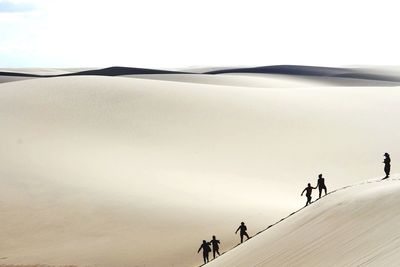 People walking on snow covered land against sky