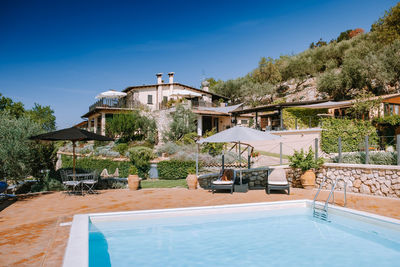 View of swimming pool by building against blue sky