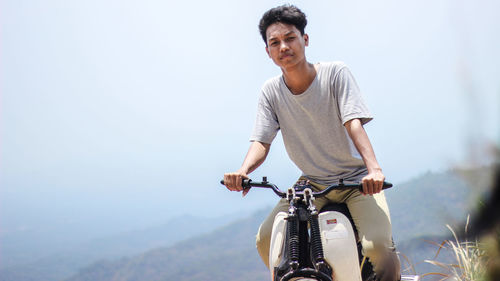 Young man riding bicycle against sky