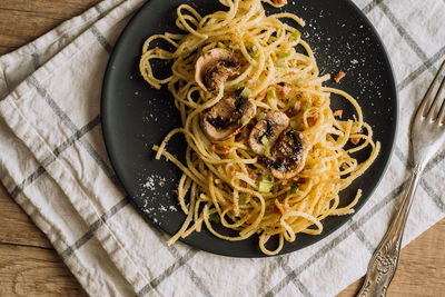 Spaghetti pasta with champignon mushrooms sprinkled with cheese parmesan and green onions