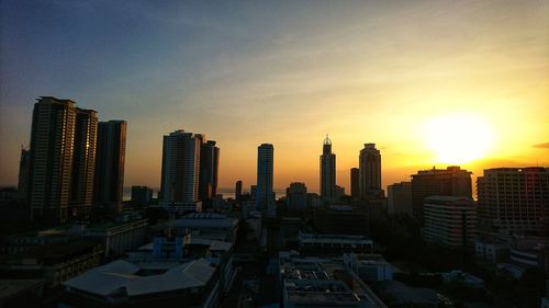 Skyscrapers in city at sunset