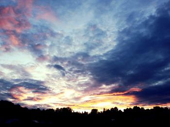 Low angle view of silhouette trees against dramatic sky