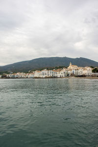 View of town in sea against cloudy sky