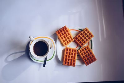 High angle view of coffee with waffles served on table