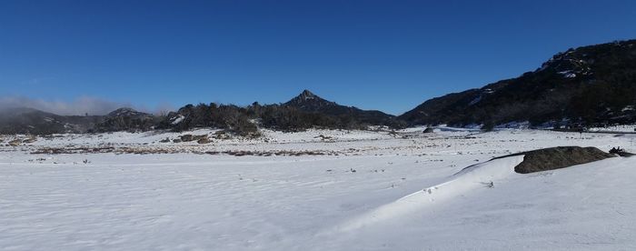 Scenic view of snow covered mountains against clear blue sky