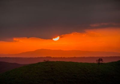 Scenic view of field against orange sky