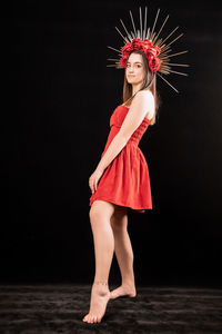 Full length portrait of woman standing against black background