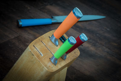 High angle view of colorful kitchen knives in rack on wooden table