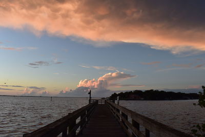 Pier over sea against sky during sunset