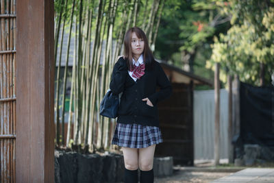 Portrait of a young woman standing against wall