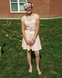 Full length of young woman standing in front of grassy field