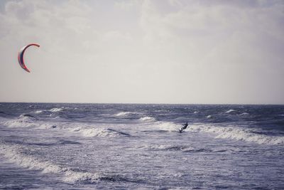 Man kiteboarding at sea against sky