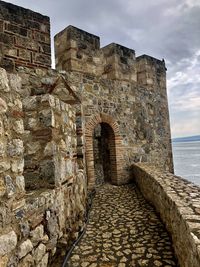 Stone wall of historical building against sky