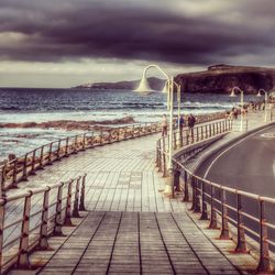 Footpath leading towards sea against sky